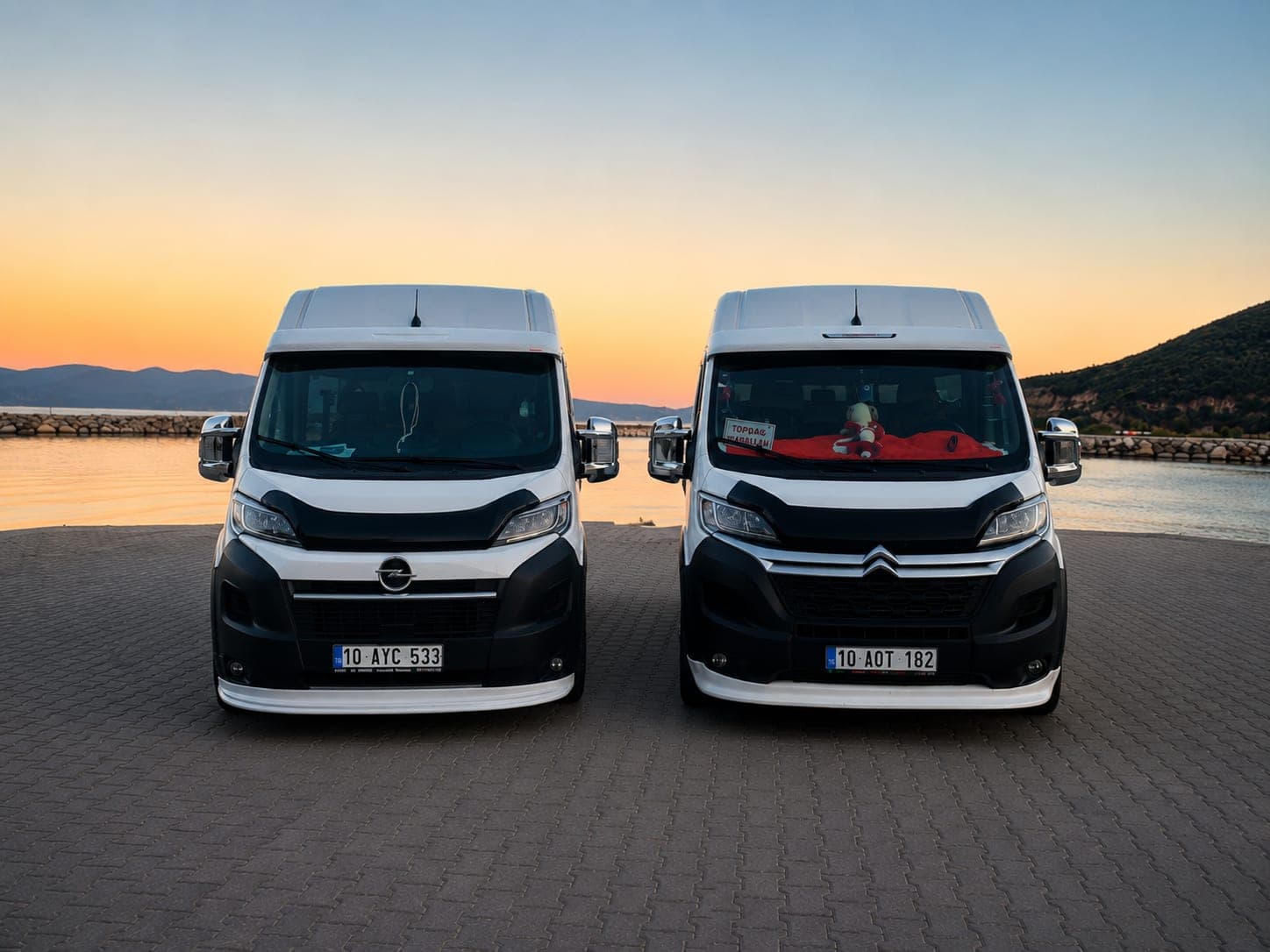 SEFATUR'un iki minibüsü, Opel Movano ve Citroën Jumper, gün batımında sahilde yan yana
